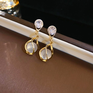 Détail de boucles d'oreilles goutte en œil de chat avec cadre doré et clous en zircone