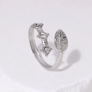 Detail of silver leaf ring with round zircon stone on white textured stone surface