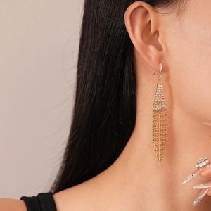 Vue détaillée de boucles d'oreilles à pompons dorés avec accents triangulaires en zircon