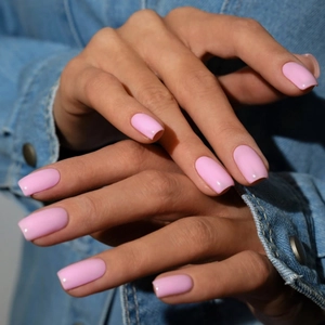Close-up of elegant square pink press-on nails worn with a casual denim jacket style