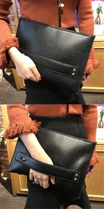 Detail van zwarte clutch van generfd leer met handgreep en gouden vierkante studs