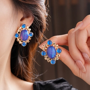 Detail of vintage gold earrings with blue opal-like stone worn by a model