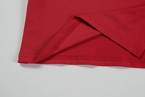 Close-up of red knit fabric showing precise double-needle stitching on the garment hem