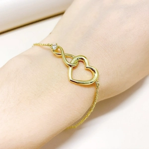 Elegant gold infinity heart bracelet with single zircon on woman's wrist