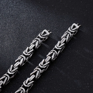 Macro shot of silver Byzantine chain with textured geometric clasp on dark background