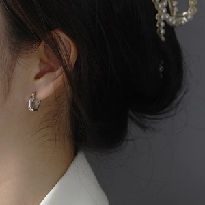 Close-up of minimalist S925 sterling silver twisted hoop earrings worn by a model