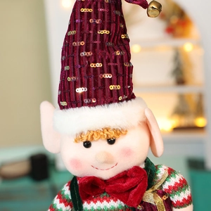Close-up of plush Christmas elf dolls with sequins and bows against warm festive lights