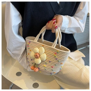 Detail of woven beige cotton handbag with colorful dots and yellow flower charm decoration