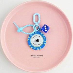 Macro shot of blue poker chip keychain with lucky dice on a pink ceramic plate