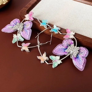 Vue détaillée de créoles avec papillon brodé violet et décorations en strass brillants