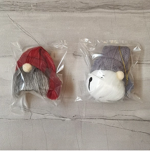 Close-up of red and grey Christmas gnome bell ornaments with gold hanging ropes