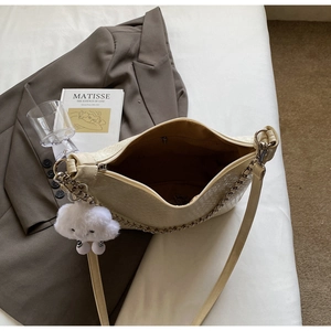Chic beige woven PU leather tote bag with cloud charm on dark grey blazer