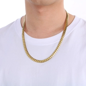 Close-up of gold-plated flat Cuban NK link necklace worn by a model on a white tee