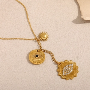 Detailed macro view of 18K gold plated tassel eye and sun pendants on a metal chain