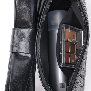 Close-up of black glossy bow crossbody bag showing zipper and cosmetic storage capacity