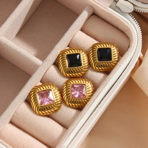Macro shot of 18K gold plated earrings with pink and black zircon in a velvet box