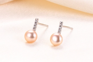 Macro shot of s925 silver bar earrings featuring pink orange pearls and sparkling stones