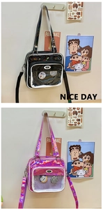 Vue détaillée du sac ita avec fenêtre transparente, badges en métal et large bandoulière réglable
