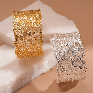 Detailed view of wide irregular mesh hollow bracelets in gold and silver on white stone