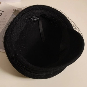 Detail of wool beret with black mesh veil showing inner sweatband and care label