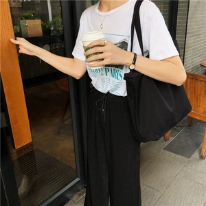 Detalle de atuendo casual con un bolso tote grande de lona negra y camiseta blanca