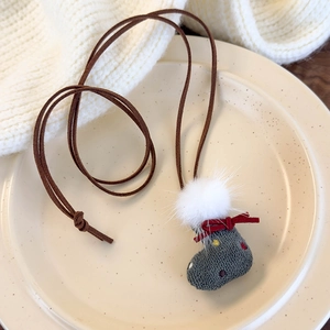 Detail of gray fabric Christmas stocking pendant with white pompom and red bow on cord
