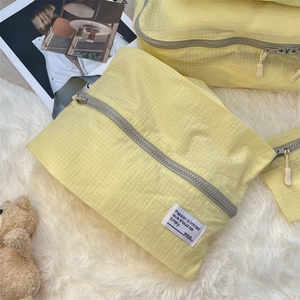 Close-up of light yellow nylon travel organizer bag with zipper and grey strap