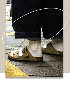 Gros plan sur des sandales en daim kaki portées avec des chaussettes blanches en coton
