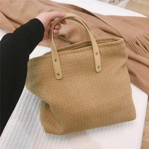Macro shot of textured beige woven tote bag with durable leather handle and gold rivet