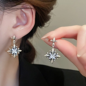 Close-up of vintage silver fleur-de-lis earrings with clear zircon stones on ear