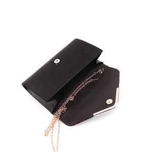 Elegant black satin evening clutch bag with gold chain strap shown open on white background