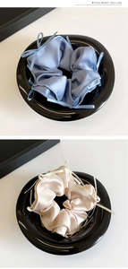 Close-up of blue and champagne satin scrunchies with delicate ribbon bow details