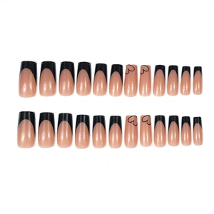 Classic black French tip press-on nails with heart designs in a long coffin shape