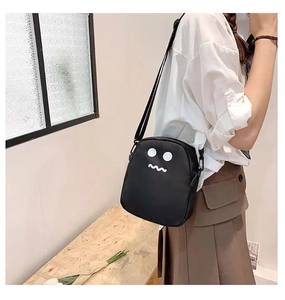 Vue latérale d'un joli sac à bandoulière noir avec motif dessin animé porté par un mannequin
