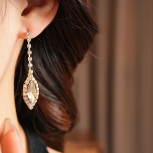 Close-up of golden teardrop tassel earrings with sparkling rhinestones on model