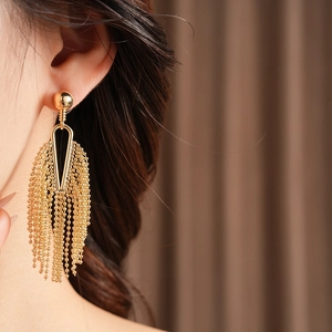 Close-up of elegant gold tassel earrings with bead chains worn by a female model