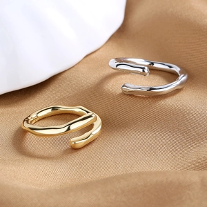 Minimalist irregular wavy open rings in gold and silver finish on silk background