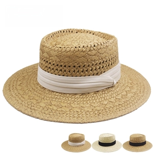 Detail of woven straw boater hat featuring a flat top and decorative ribbon band