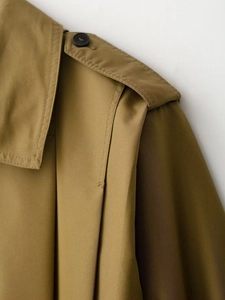 Dettaglio spallina e design a pieghe su collo alto di trench color kaki per donna