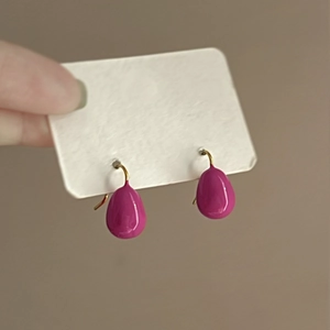 Detail of pink teardrop earrings with golden hooks held on a white display card