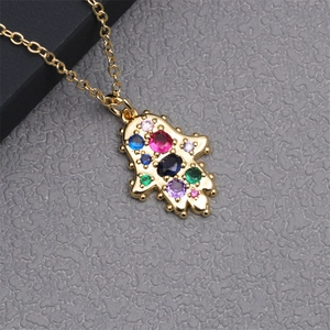 Macro shot of gold Hamsa hand pendant necklace with colorful micro-inlaid cubic zirconia stones