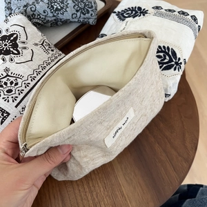 Linen canvas cosmetic pouch detail showing internal space with a silver makeup compact