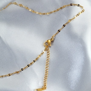 Detailed macro view of the gold necklace lobster clasp and adjustable extension chain