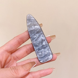 Close-up of grey marble pattern resin hair clip held by hand showing fine texture