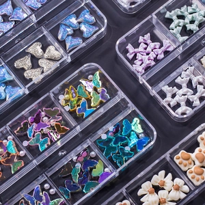 Macro shot of assorted nail art charms including resin hearts and bows in a clear box