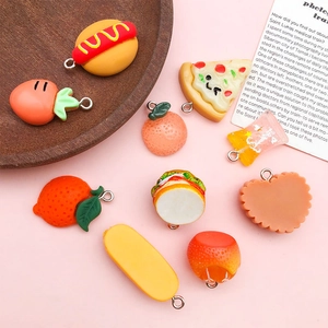 Close-up of resin food pendants including pizza and orange on a wooden tray