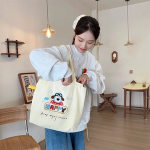 Close-up of cute dog embroidery on a beige canvas tote bag with drawstring detail