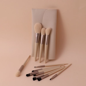 Close-up of professional makeup brushes with rose gold ferrules and a nude leather pouch