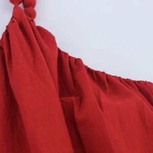 Detailed macro view of the red woven fabric texture and pleats on the strap dress
