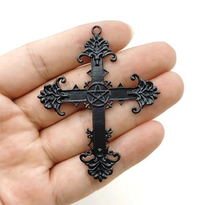 Macro shot of Gothic black cross pendant with star symbol and vintage floral patterns